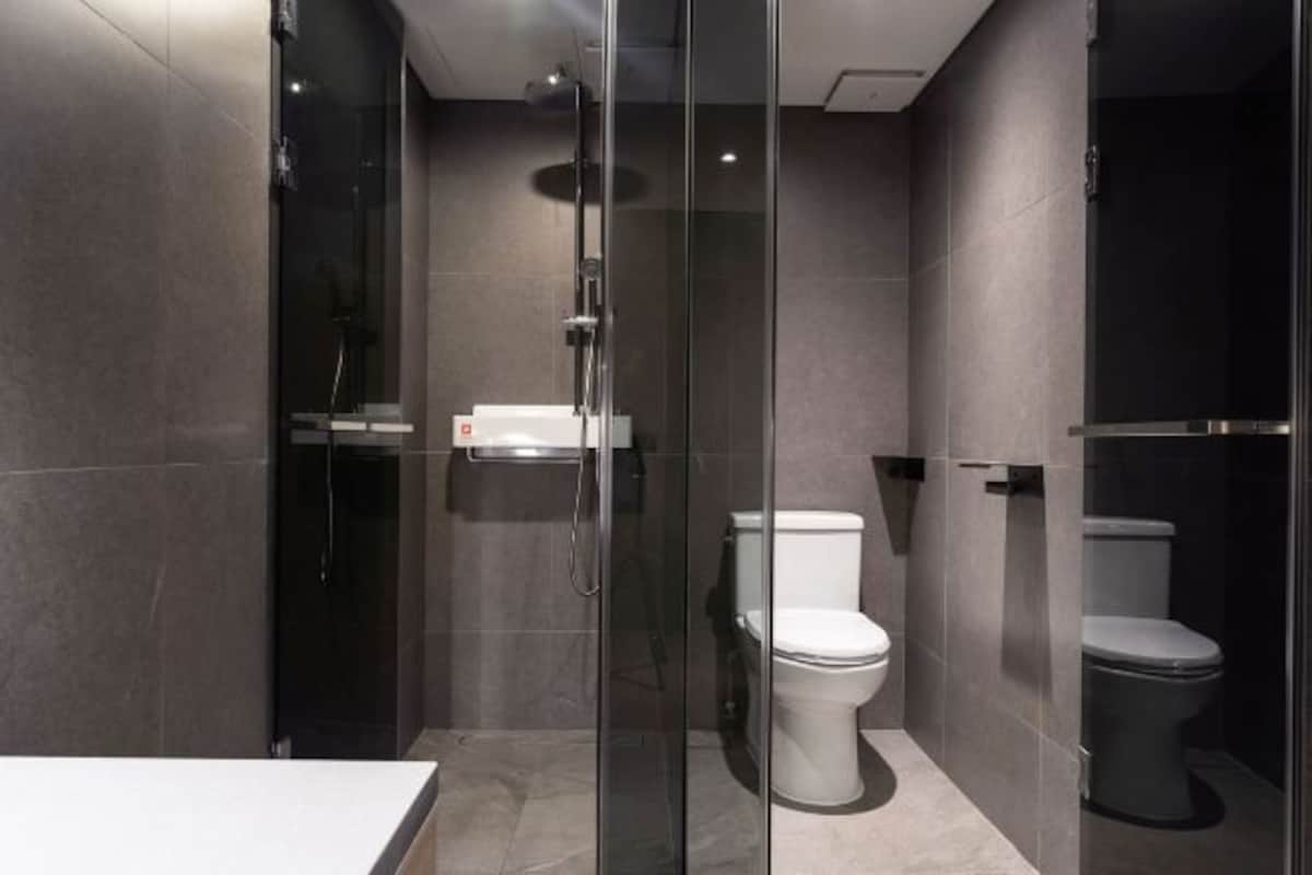 A modern bathroom with a glass-enclosed shower, a white toilet, and a white sink.