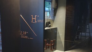 A modern hotel entrance with a glass door, a reception desk, and a visible staircase. - H hotel (Seoul)