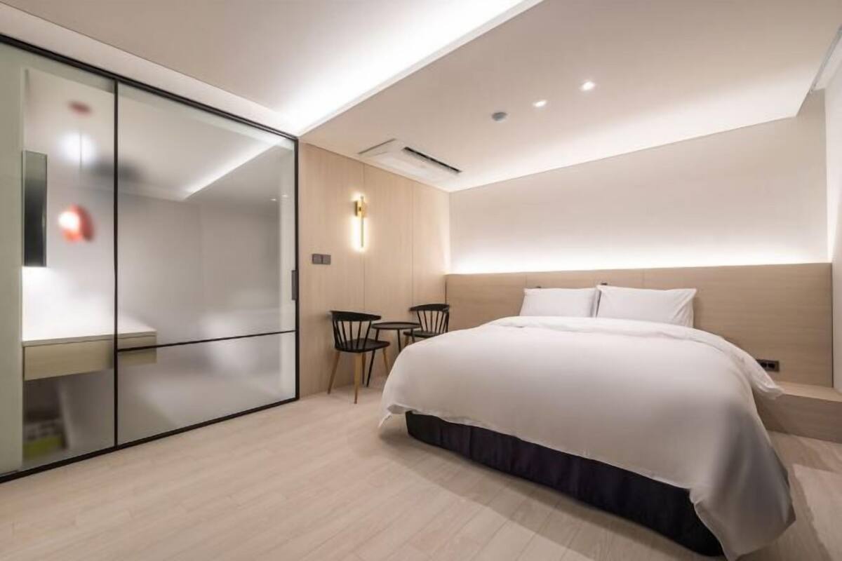 A modern hotel room with a bed, a desk, and a chair.