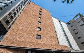 Un grand immeuble en briques, doté d’une façade moderne, de nombreuses fenêtres et d’une enseigne indiquant qu’il s’agit d’un hôtel de catégorie moyenne.