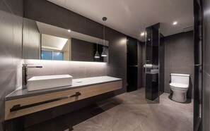 A modern bathroom with a large mirror, a wooden vanity, a white sink, and a toilet. - H hotel (Seoul)