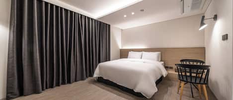 Una habitación de hotel moderna con una cama grande, un escritorio y una silla.