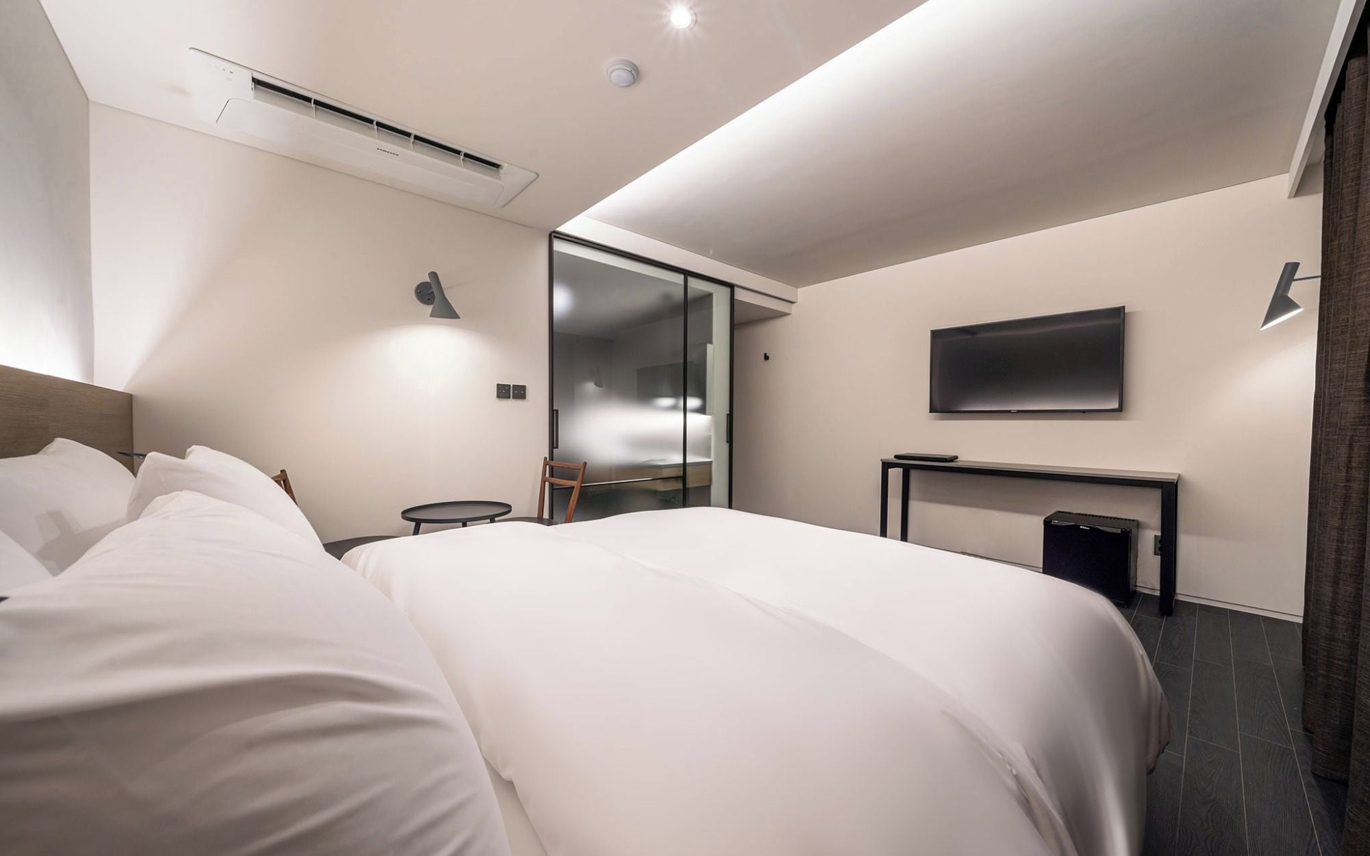 Une chambre d’hôtel moderne dotée d’un grand lit, d’un téléviseur à écran plat, d’un bureau et d’une porte coulissante donnant accès à la salle de bain.
