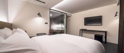 Une chambre d’hôtel moderne dotée d’un grand lit, d’un téléviseur à écran plat, d’un bureau et d’une porte coulissante donnant accès à la salle de bain.