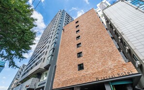 A building with a brick facade and a sign indicating it is a hotel. - H hotel (Seoul)