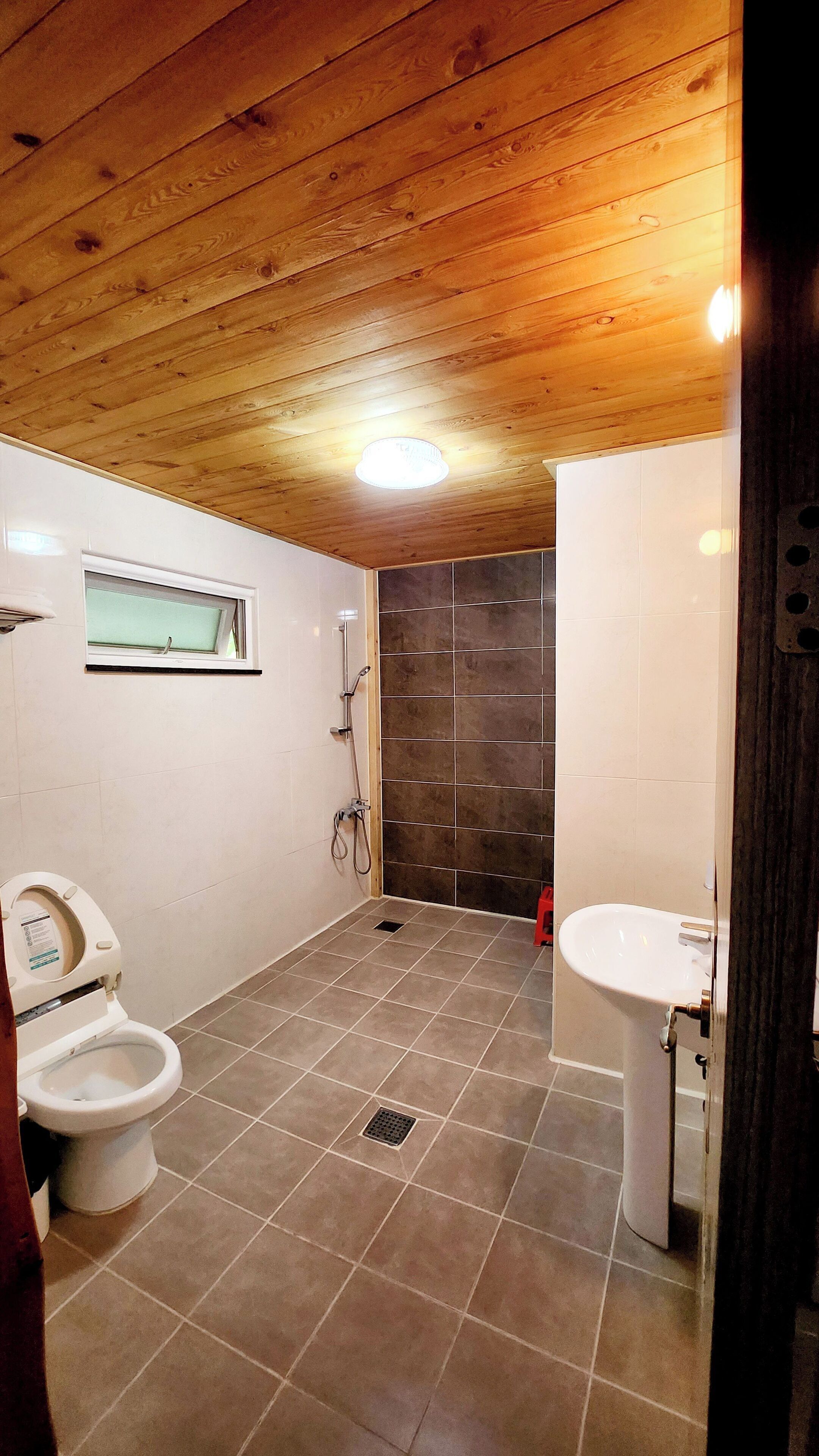Une salle de bain avec un plafond en bois, une douche, des toilettes et un lavabo.