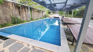 A rectangular swimming pool with a clear blue water surface, surrounded by a stone border.