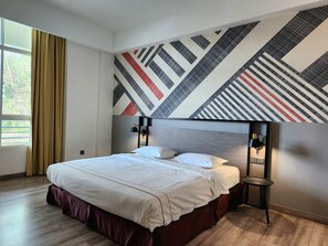 A modern hotel room with a large bed, a patterned wall, and a window with curtains. - K Hotel (Kota Kinabalu)
