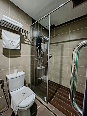A modern bathroom with a glass-enclosed shower, a toilet, and a towel rack with a hotel towel. - K Hotel (Kota Kinabalu)
