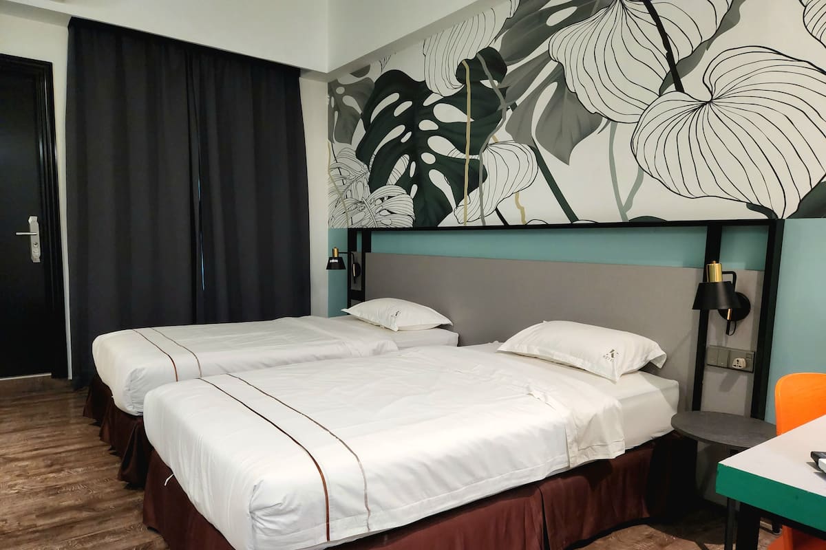 A hotel room with two beds, a desk, and a chair.