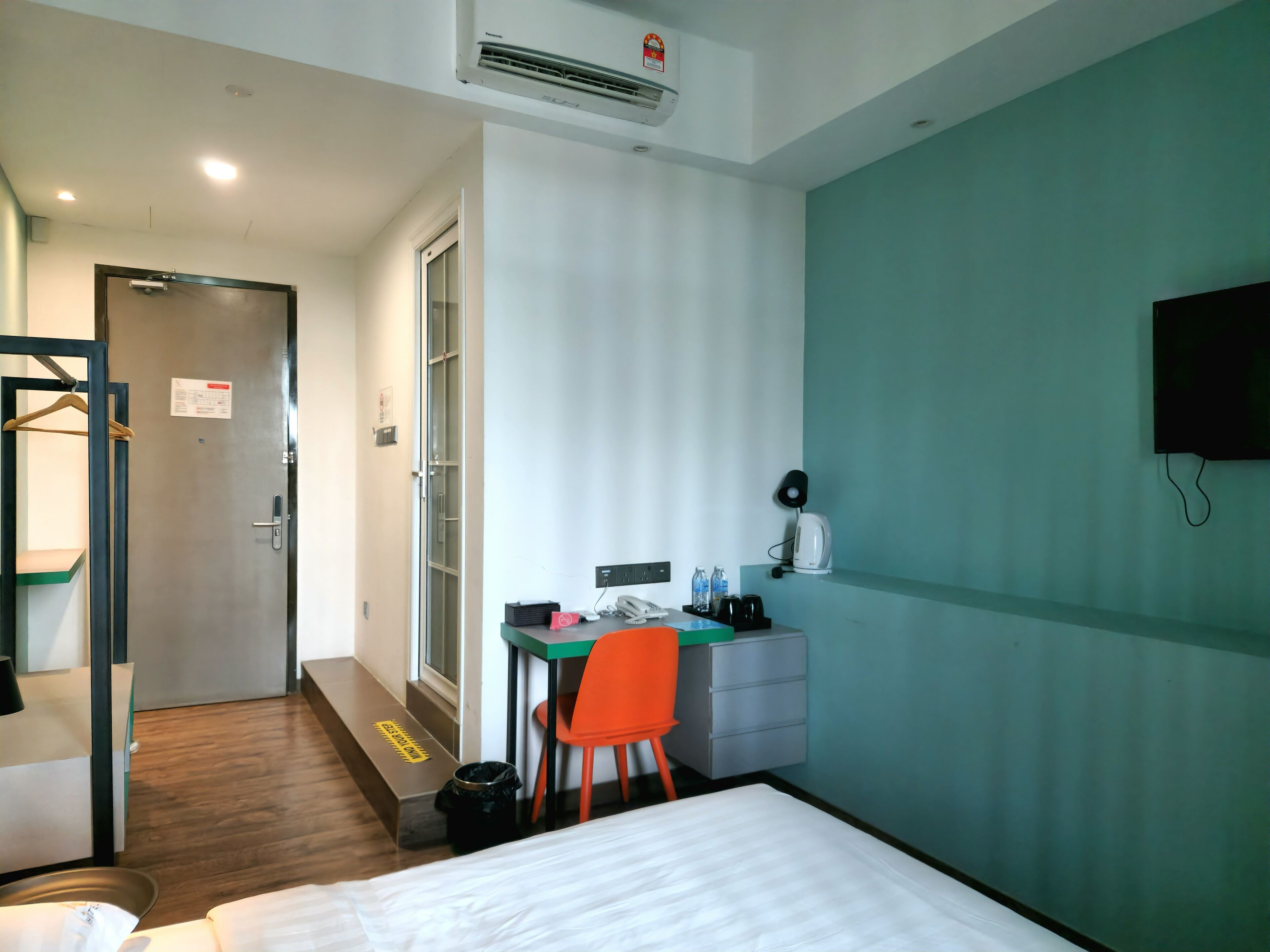 Une chambre d’hôtel comprenant un lit, un bureau avec une chaise, une télévision et une petite kitchenette.