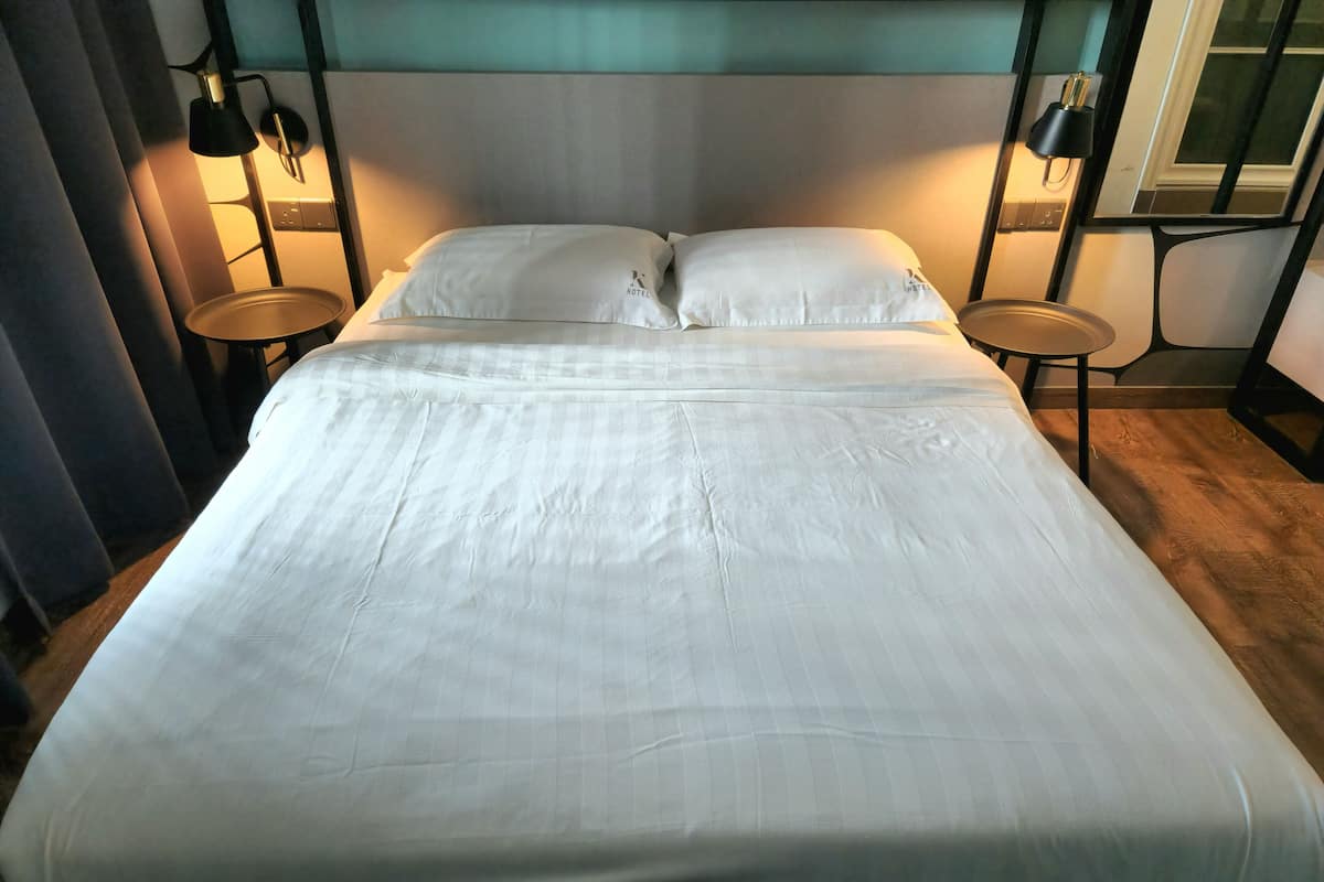 A neatly made bed with white linens in a hotel room.