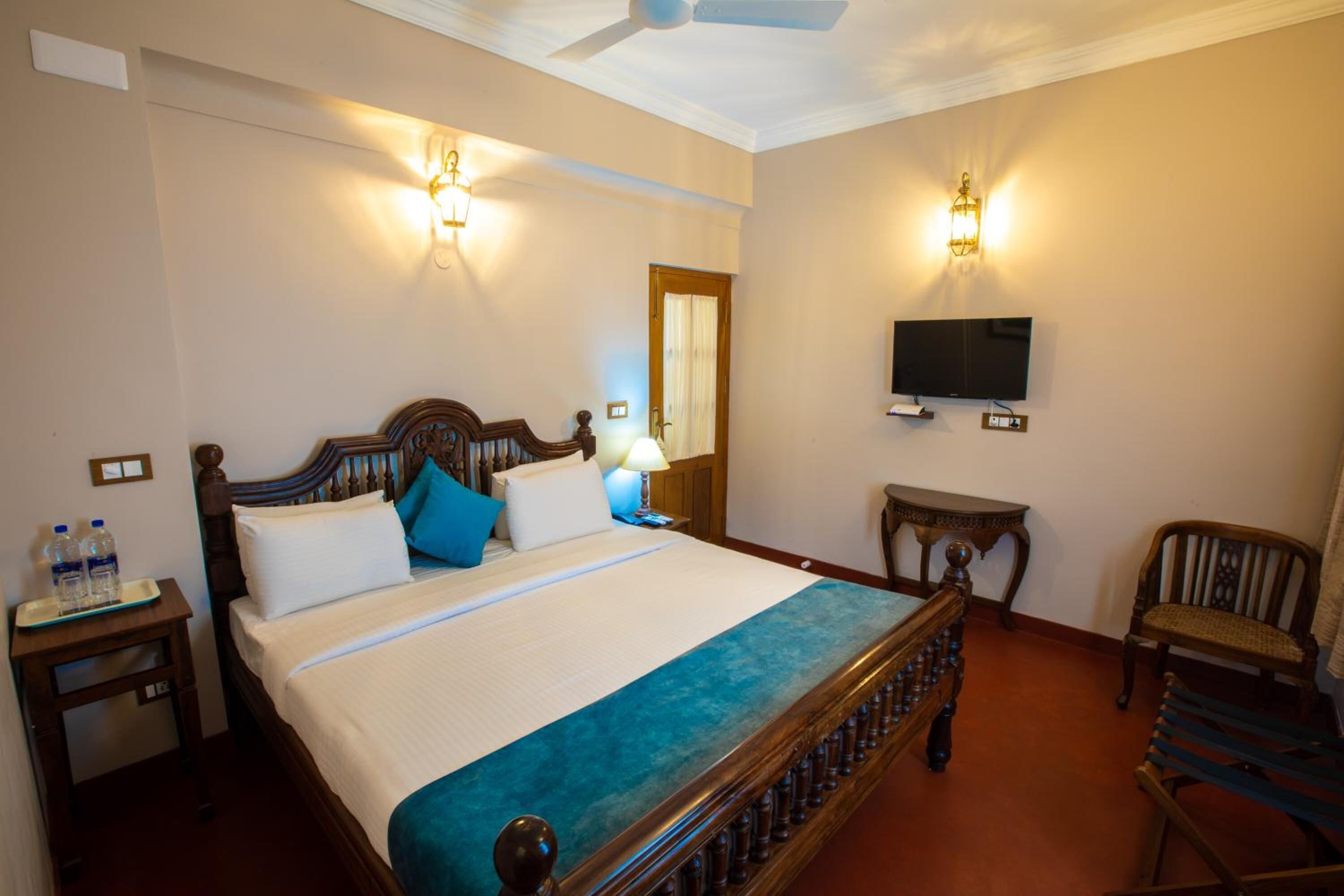 A neatly arranged hotel room with a large bed, bedside tables, a television, and a chair.