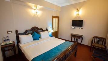 A neatly arranged hotel room with a large bed, bedside tables, a television, and a chair.