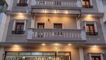 A multi-story residential building with balconies, a gated entrance, and a sign indicating a restaurant.