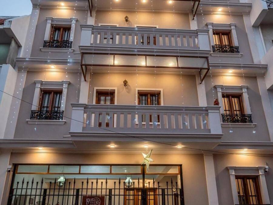 A multi-story residential building with balconies, a gated entrance, and a sign indicating a restaurant.