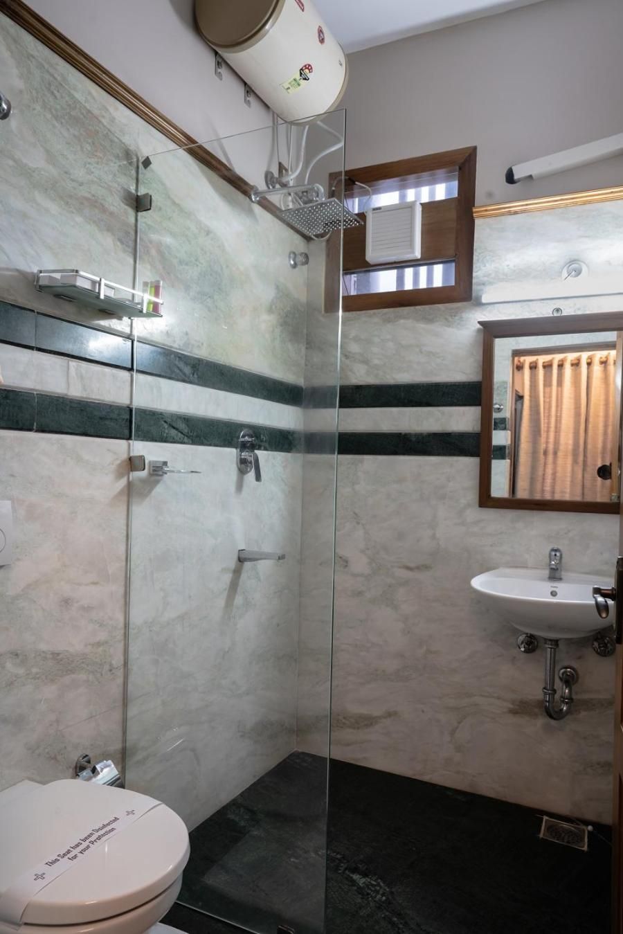 A bathroom with a glass-enclosed shower, a white sink, and a toilet with a beige lid.