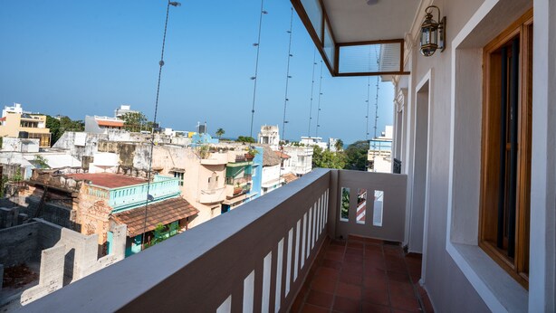 Varanda com vista para a paisagem urbana, com piso de azulejos e guarda-corpo.