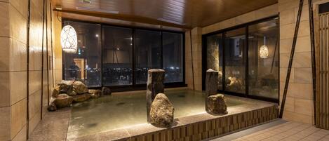 A modern interior with a stone bath area, large windows, and wooden ceiling.
