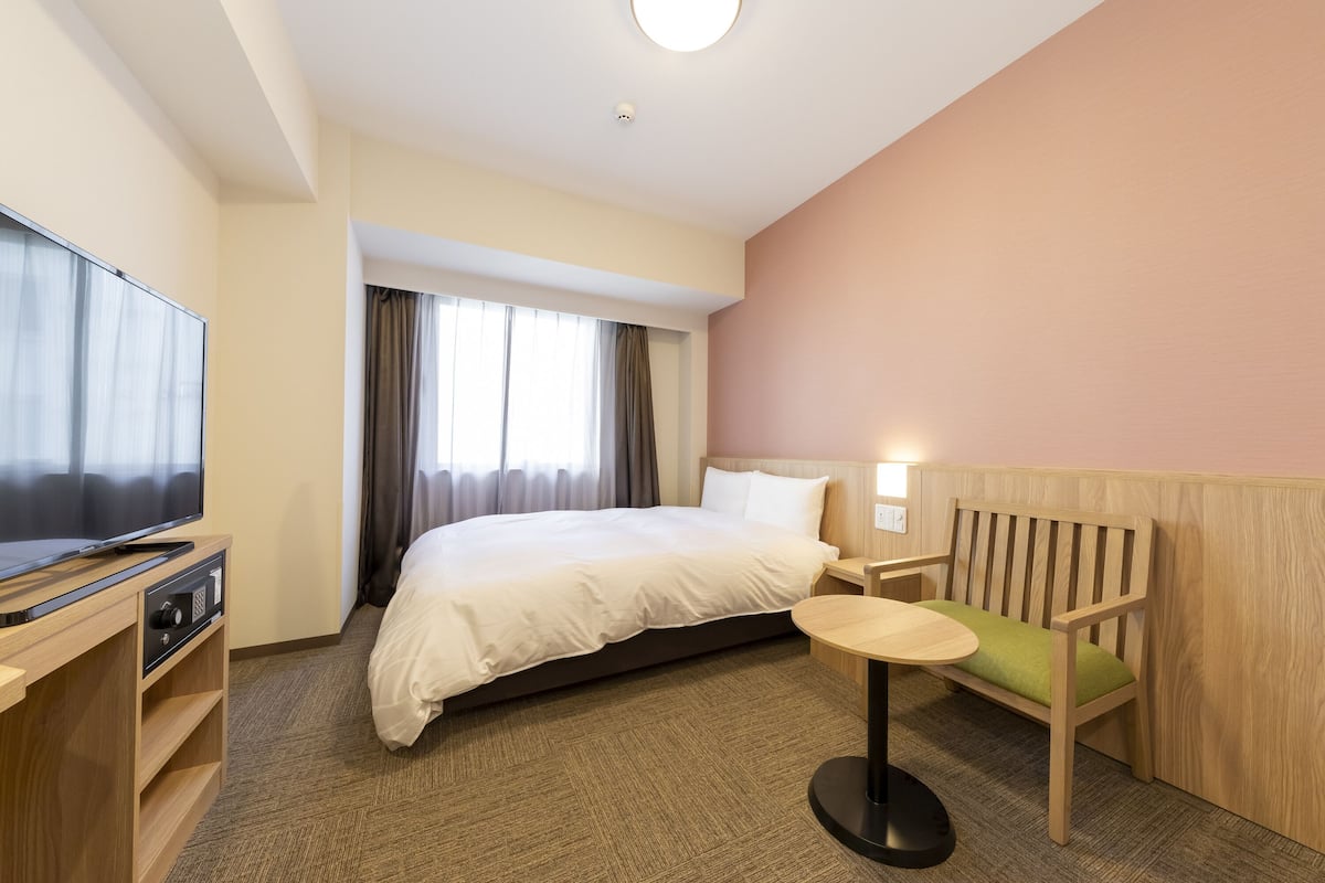 A hotel room with a bed, a television, a desk, and a chair.