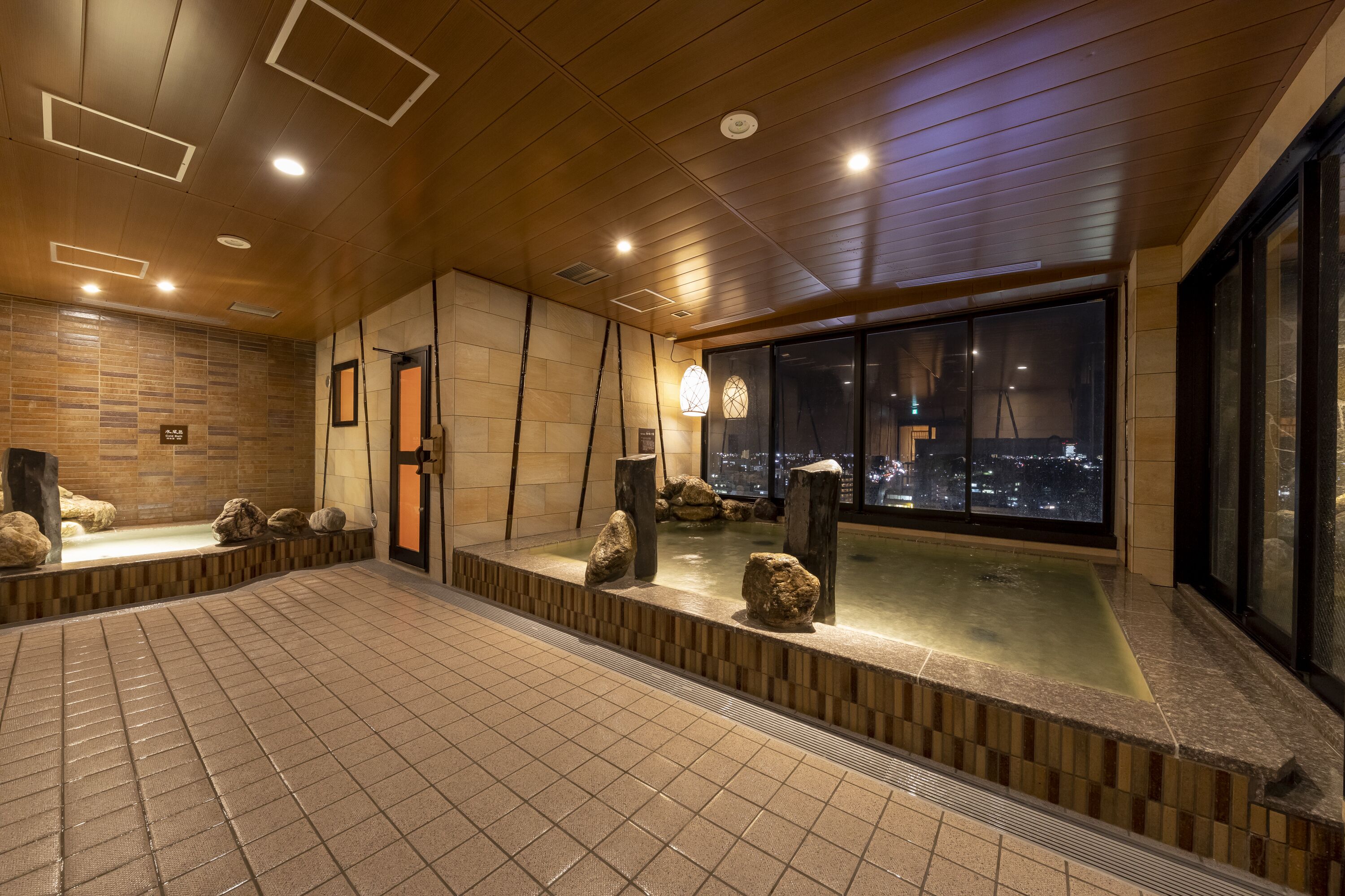 Un spa modern amb una banyera de pedra, sostre de fusta i vistes a la ciutat.