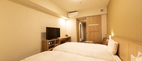 A hotel room with two beds, a TV, a desk, and a small table.