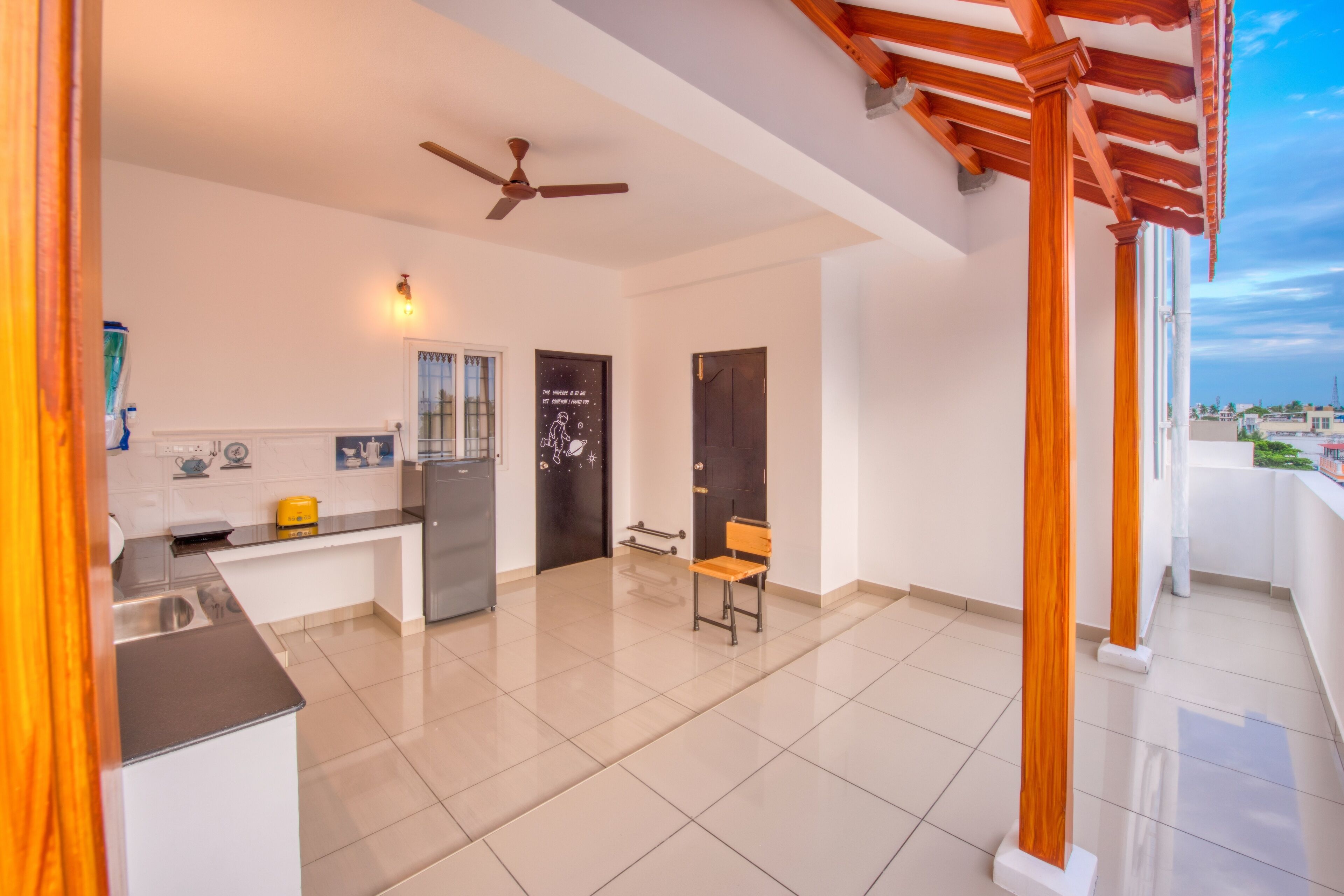 Una cocina moderna con refrigerador empotrado, un banco de madera y un ventilador de techo.