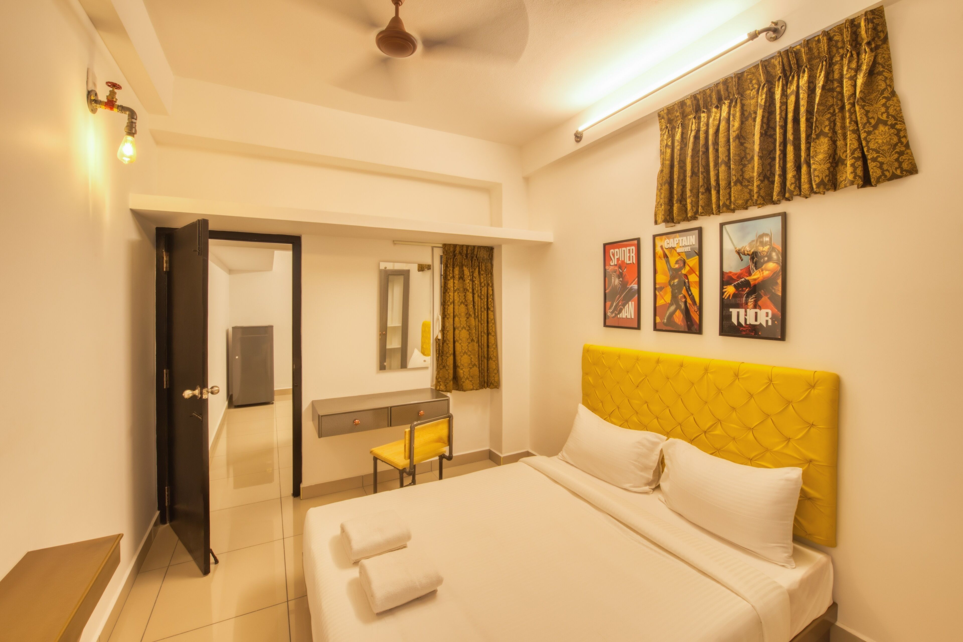 A hotel room with a bed, a desk, a chair, a mirror, and a shower area.