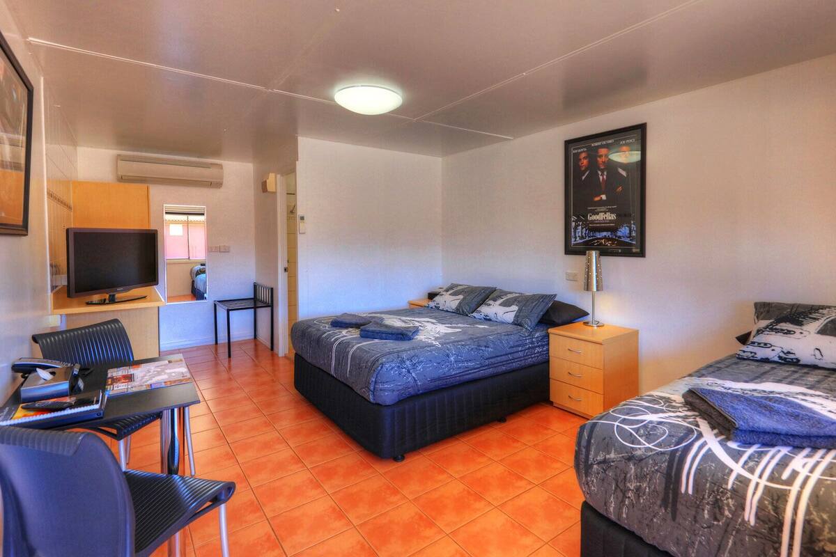 A compact hotel room with a bed, a desk, a chair, and a television.