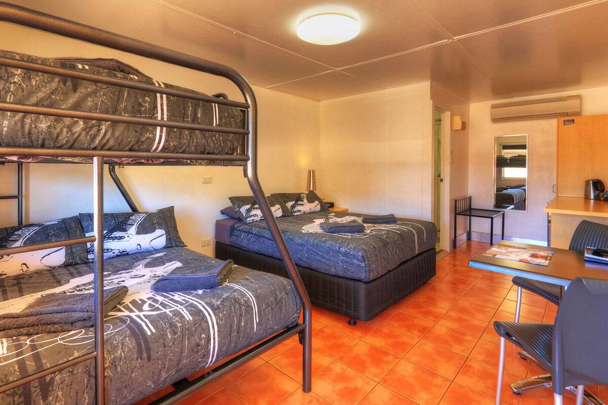 A dormitory room with bunk beds, a desk, and a chair.