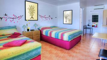 Habitación con dos camas, un escritorio y una silla. Cuenta con adornos en la pared y un equipo de aire acondicionado.