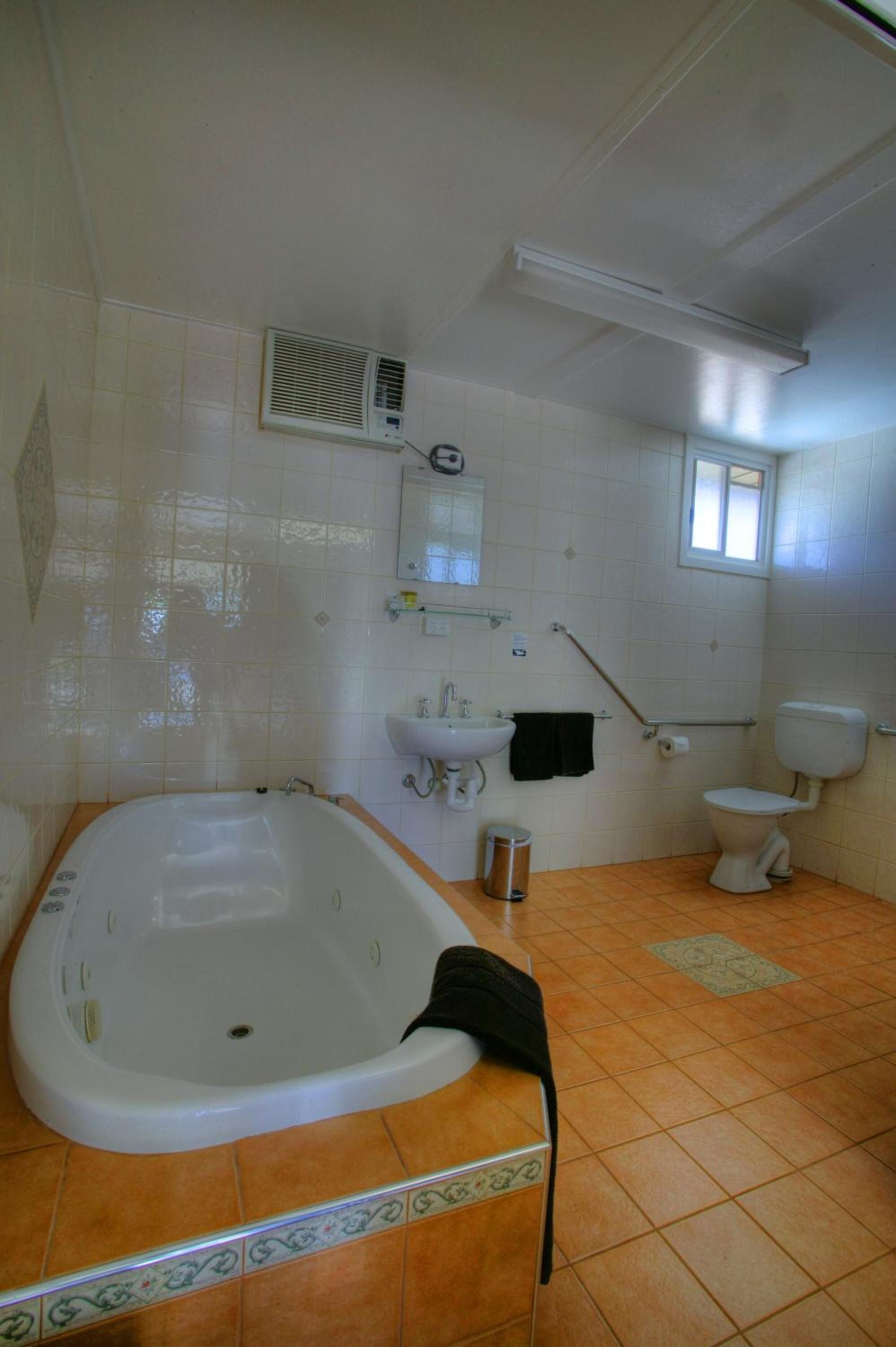 A bathroom with a bathtub, sink, toilet, and a window.