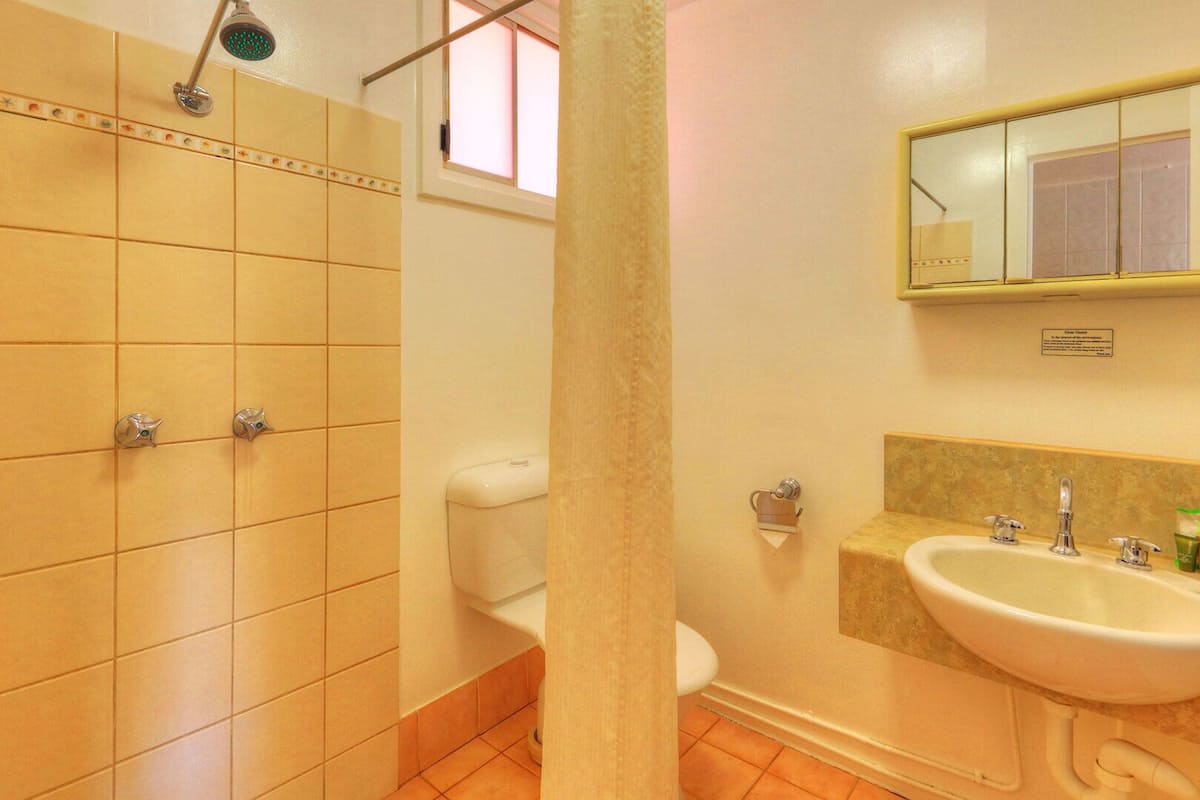 A bathroom with a shower, toilet, sink, and mirror.