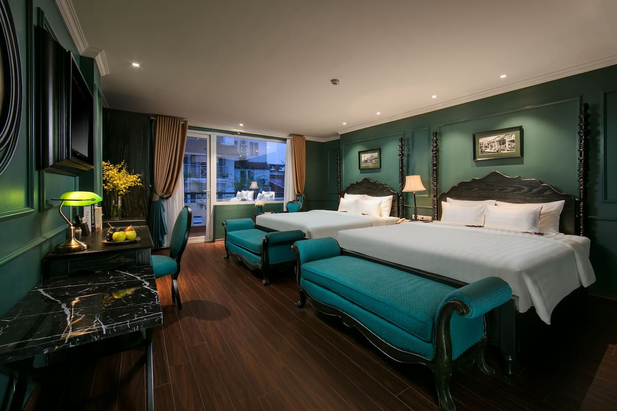 Une chambre d’hôtel avec deux lits, un bureau avec une lampe, une chaise et une vue sur l’extérieur.