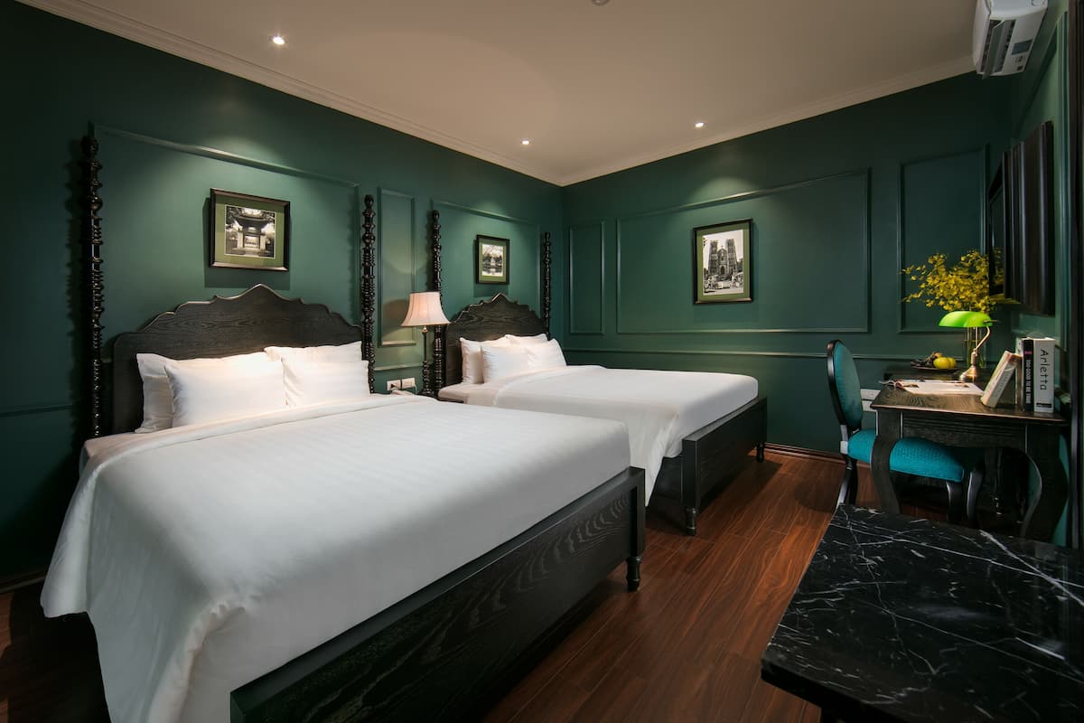 Une chambre d’hôtel avec deux lits, un bureau et une chaise.