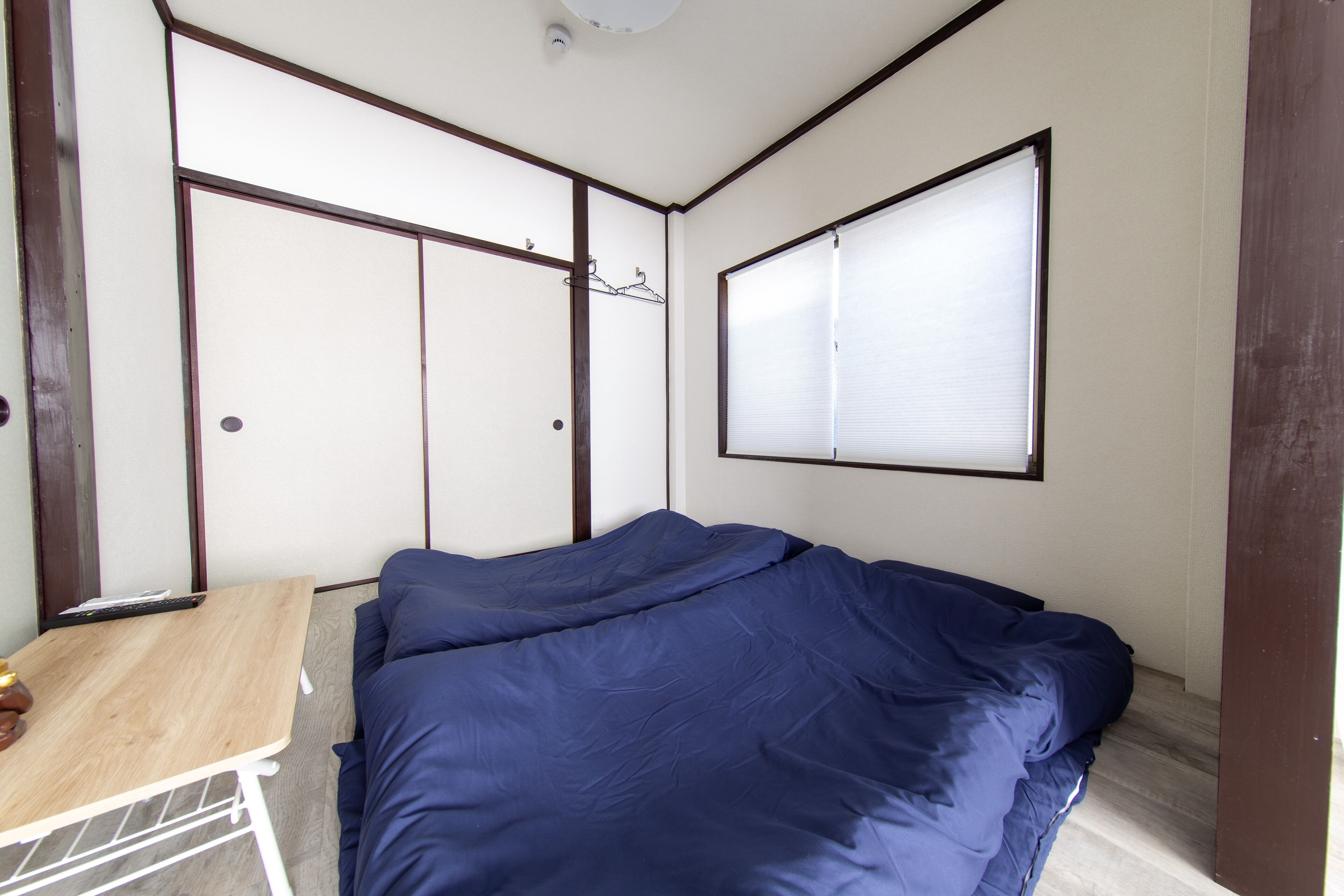A bedroom with a bed, a small table, and a wardrobe.