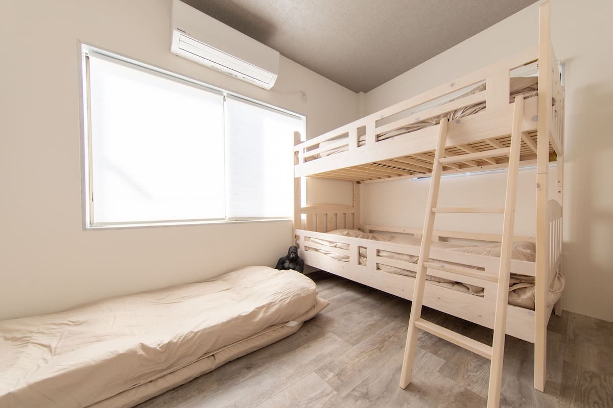 Habitación con literas, una ventana y un colchón en el suelo.
