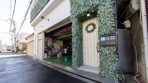 Un edificio con una puerta de garaje abierta, un letrero con caracteres japoneses y un piso verde.