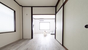 Un pasillo con suelo de madera, un inodoro y una ventana con persianas.
