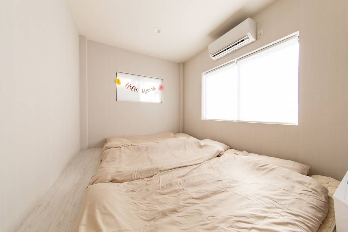 Un dormitorio con cama, ventana, aire acondicionado y un letrero en la pared.
