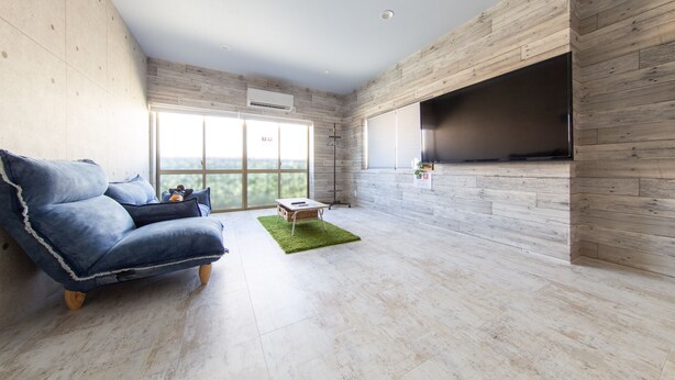 Una sala de estar moderna con un sofá azul, una mesita y un televisor montado en una pared de madera.