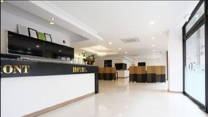 A hotel reception area with a reception desk, a chandelier, and a seating area with chairs and a table.