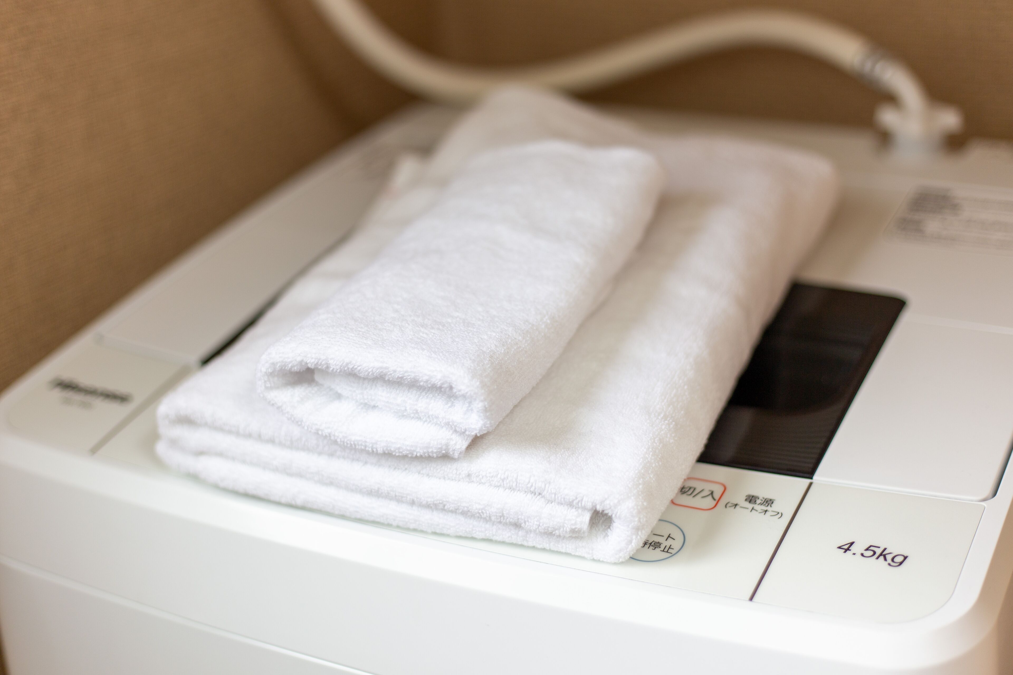 A white towel folded on a white appliance, possibly a dryer, with a label indicating a weight of 4.5kg.