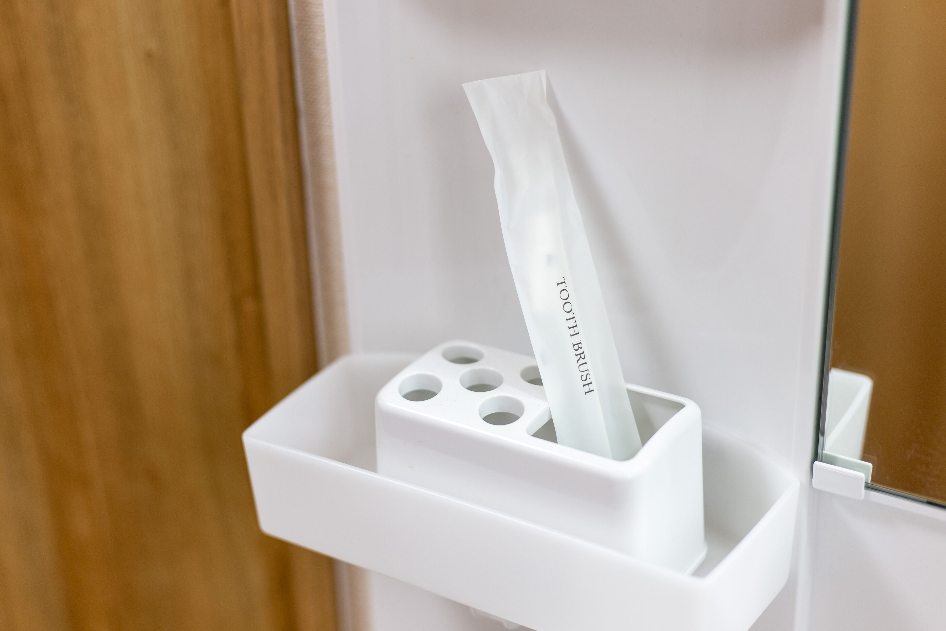 Un porte-mouchoirs blanc contenant un mouchoir sur lequel est écrit « BROSSE À DENTS », dans une salle de bain.
