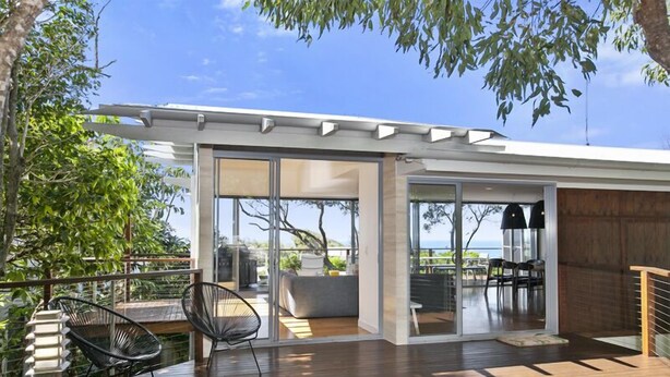 A modern house with a deck, glass doors leading to an interior space, and a view of the sea. - Stunning Seaviews, Sunshine Beach (Sunshine Beach)