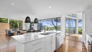 A modern kitchen with a large island, white cabinetry, and a view of the outdoors. - Stunning Seaviews, Sunshine Beach (Sunshine Beach)