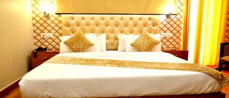 Una habitación de hotel con una cama grande, cabecero acolchado y almohadas estampadas.