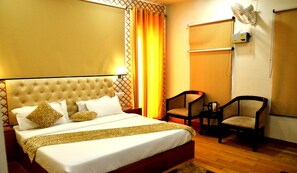 Habitación de hotel con una cama grande, dos sillas, un calefactor y una ventana con cortinas.