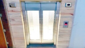 Un ascensor amb acabat metàl·lic i un panell de control amb una llum vermella.