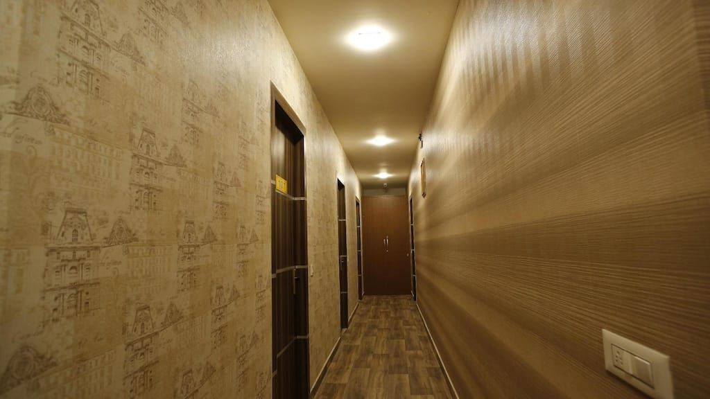 Un couloir aux murs ornés de motifs, doté d’un plancher en bois et de portes donnant accès aux différentes pièces.